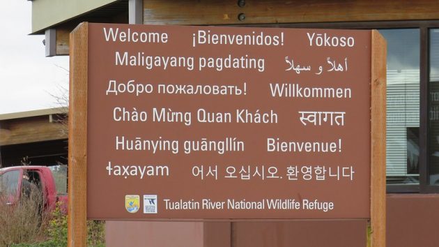 Sign at entrance of Tualatin River National Wildlife Refuge stating "welcome" in 13 languages.
