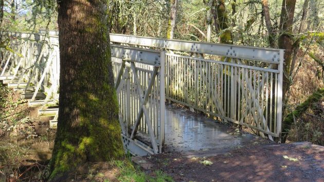 Another view of metal bridge spannig a creek. 